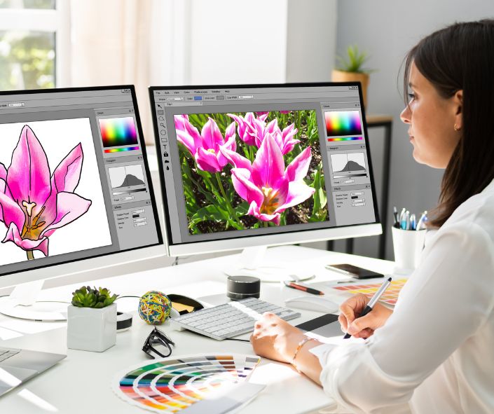 Grafiker vor zwei Bilderschirmen gestaltet ein Blumendekor.